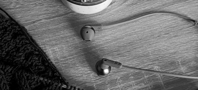 Kaffeetasse, Strickzeug und Kopfhörer.